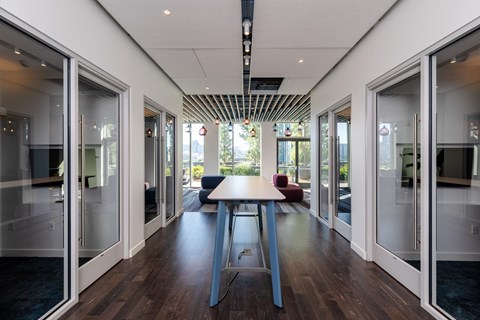 A long table is in the middle of a room with glass doors on both sides.
