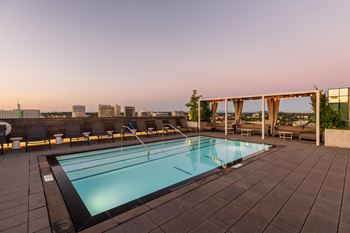 A rooftop pool with a view of the city skyline at dusk.