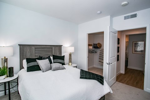 A bedroom with a large bed and a nightstand with a lamp.