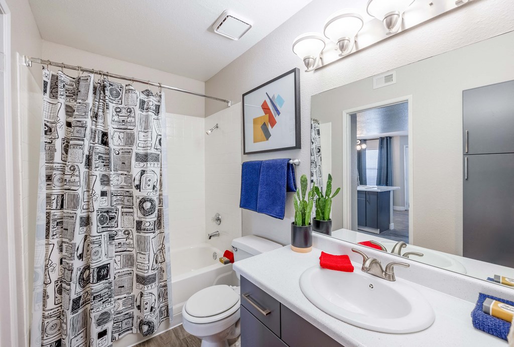 a bathroom with a white sink and toilet next to a bathtub with a shower curtain and