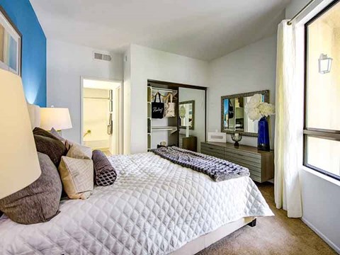A bedroom with a bed, nightstand, and mirror.
