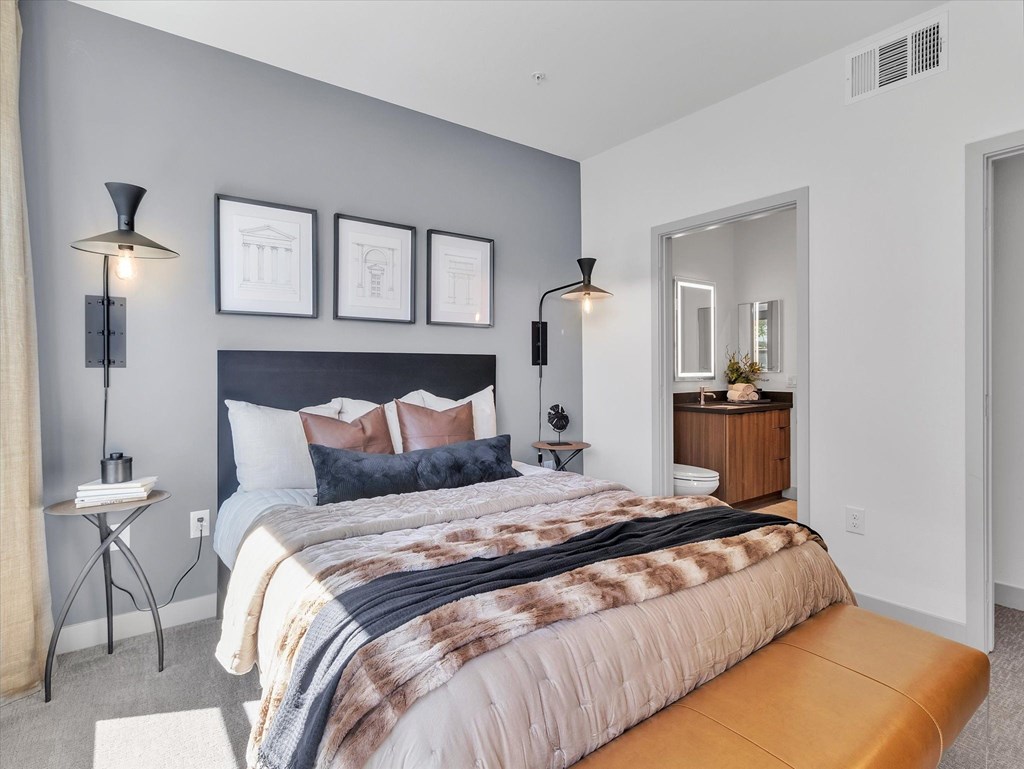 A bedroom with a large bed and a bench.