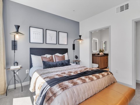 A bedroom with a large bed and a bench.