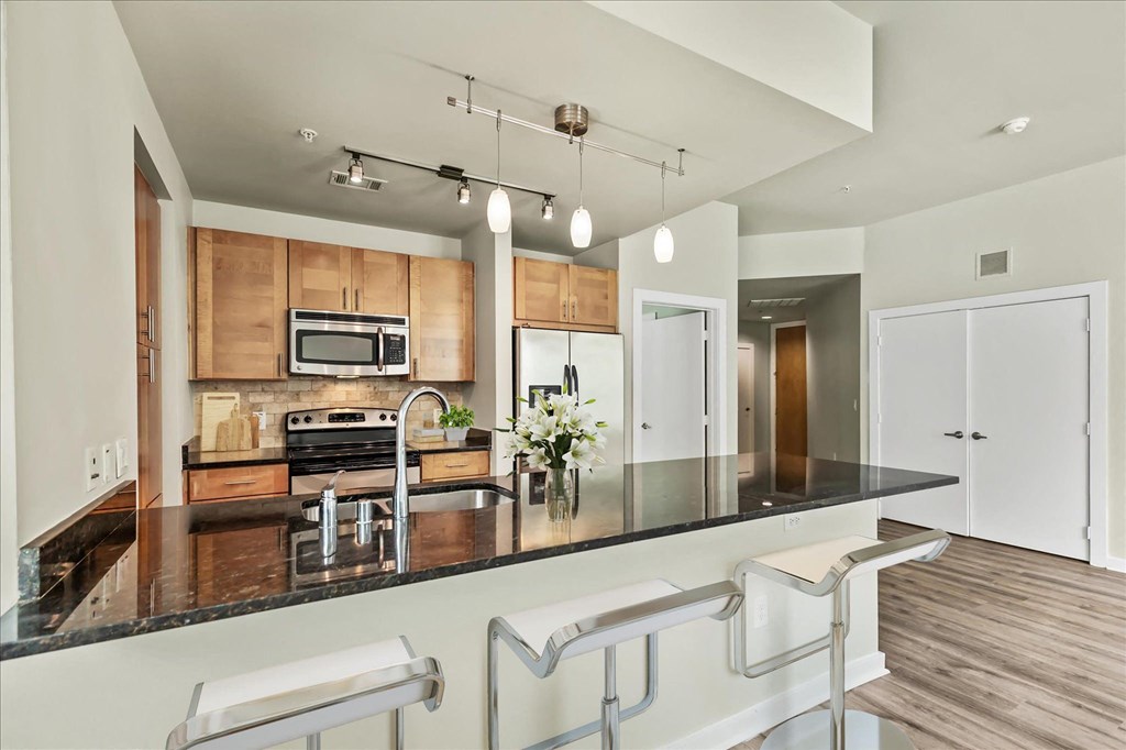 a kitchen with wood cabinetry and black countertops