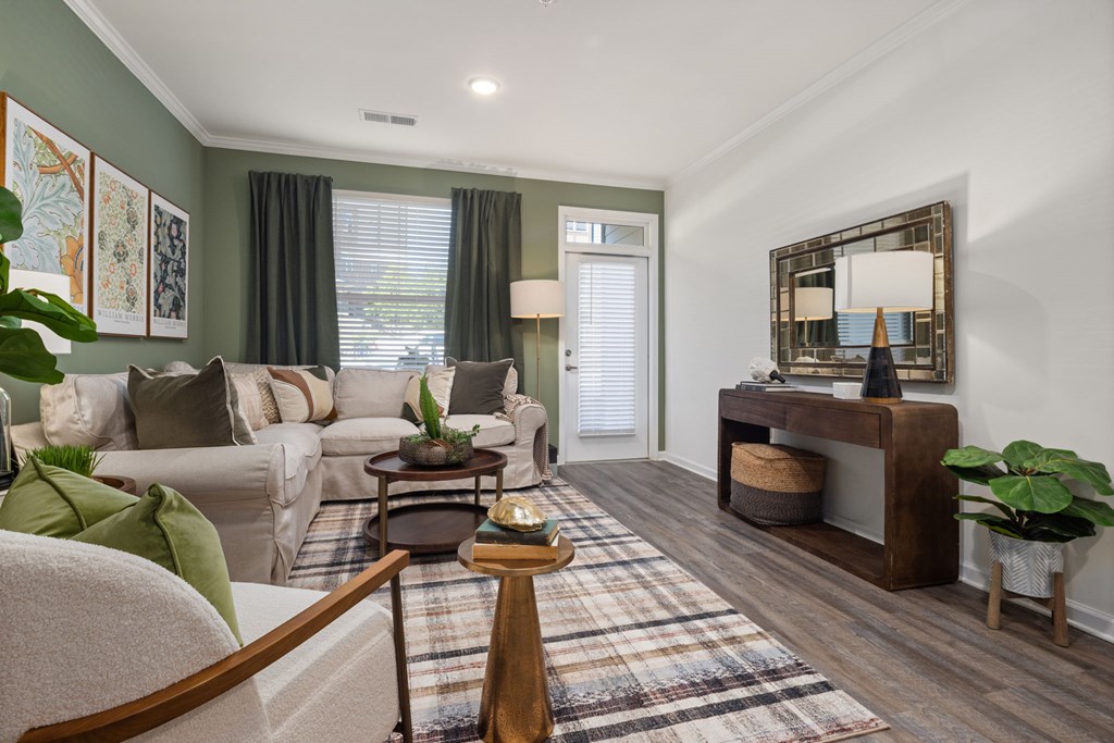 A living room with a grey sofa, a wooden table, and a mirror on the wall.