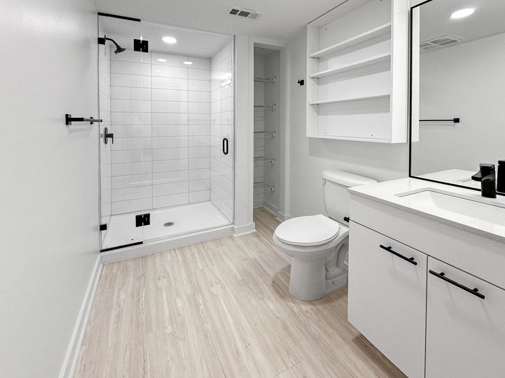 a white bathroom with a toilet and a shower