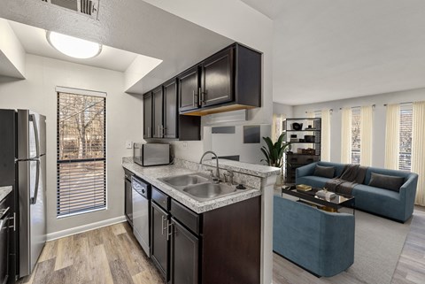 A modern kitchen with dark brown cabinets and a marble countertop.