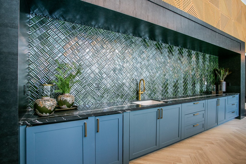 a kitchen counter top with blue cabinets and green tile on the wall