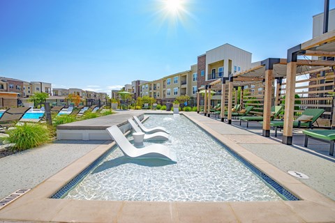 a resort style pool with lounge chairs in a large apartment building