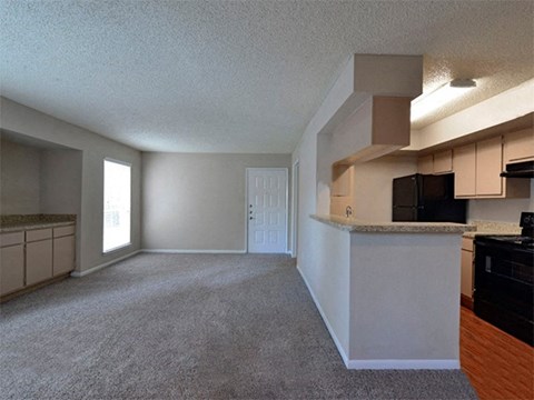 an empty living room and kitchen with a counter top