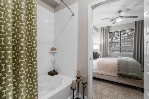 A bathroom with a shower, a bed, and a window.
