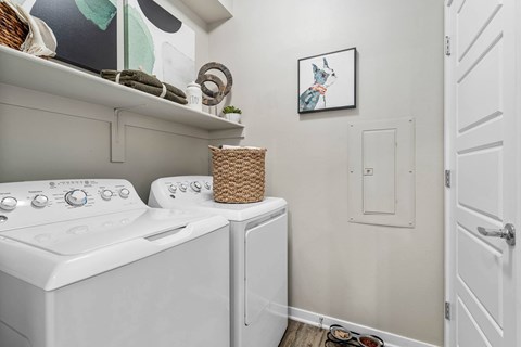 A laundry room with a washer and dryer and a basket on top of the dryer.