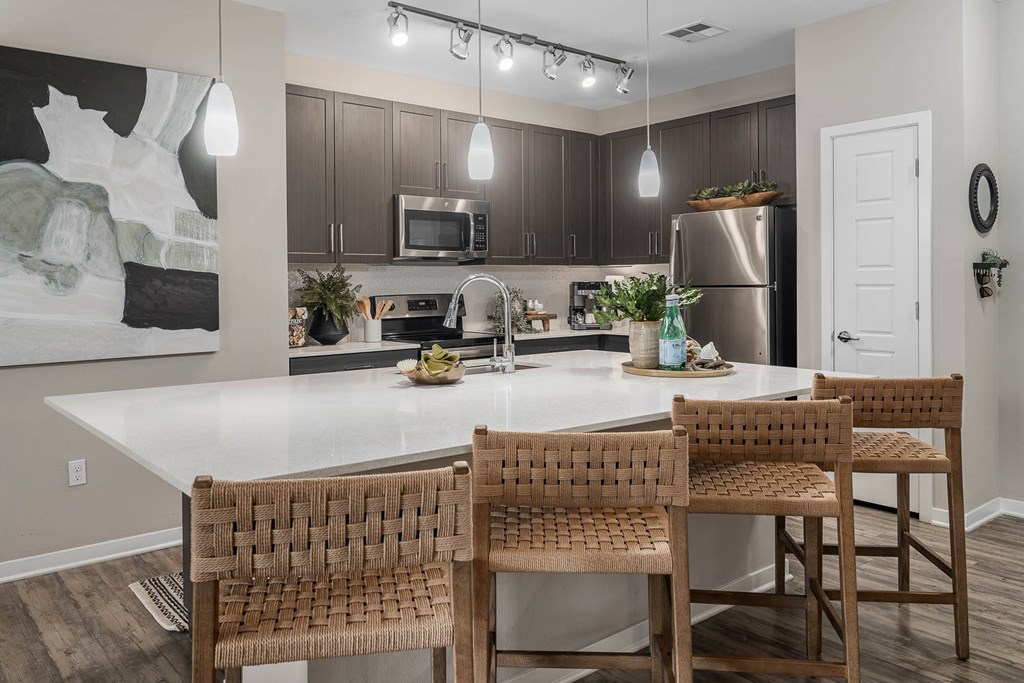 A kitchen with a white table and brown chairs.