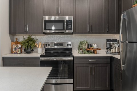 A modern kitchen with dark wood cabinets and stainless steel appliances.