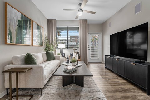 A living room with a white couch, a coffee table, and a flat screen TV.