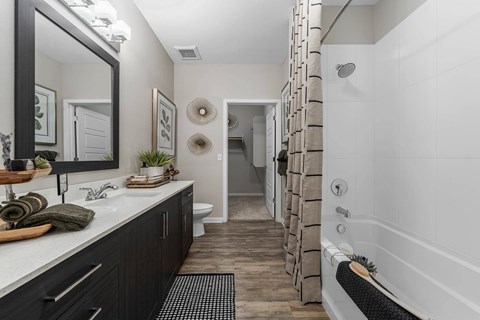 A bathroom with a white tub and a mirror above the sink.