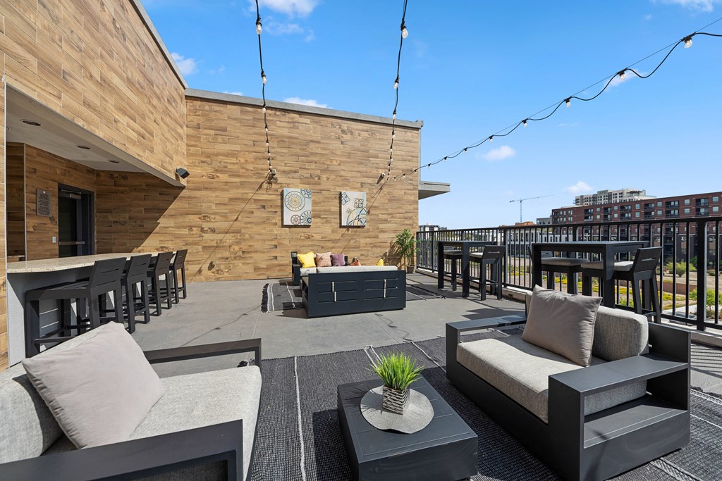 a roof deck with couches tables and chairs and a bar