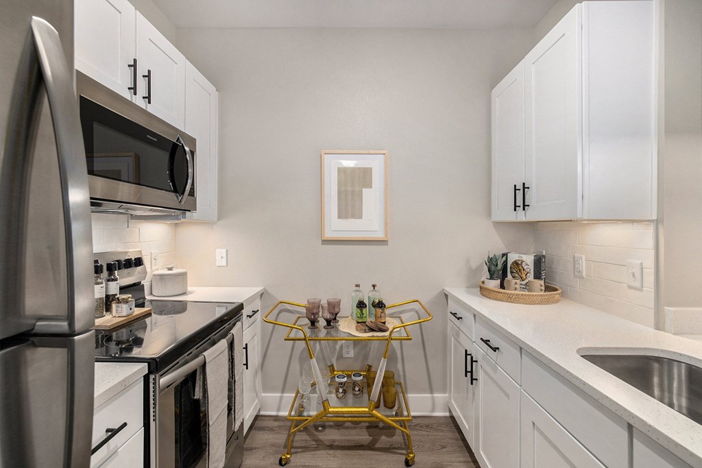 an apartment kitchen with stainless steel appliances and white cabinets