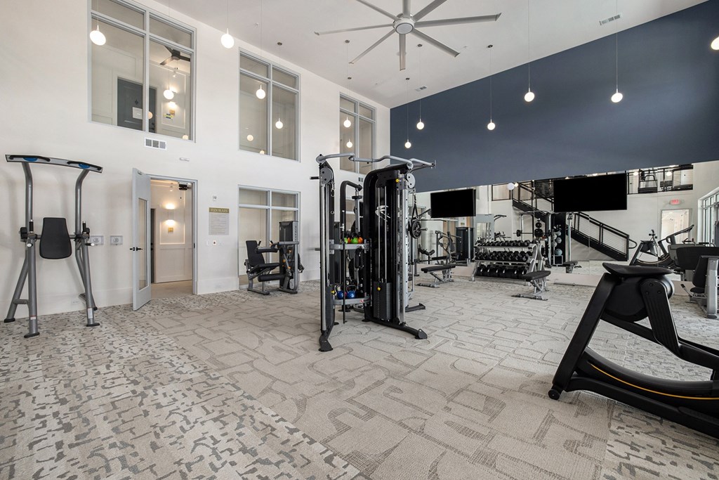 a gym with weights and cardio equipment in a building with large windows
