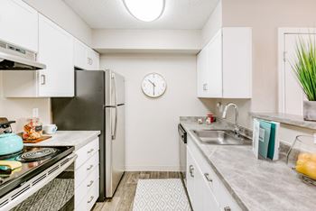 A kitchen with a black refrigerator and white cabinets.