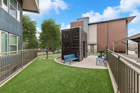 A small grassy area with a bench and a tall black structure.