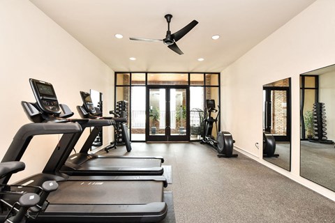a gym with treadmills and a ceiling fan