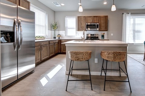 a kitchen with stainless steel appliances and a counter with two stools