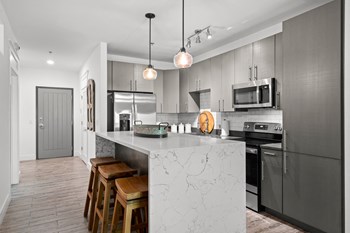 River Mill Lofts Kitchen Kitchen with grey cabinets, waterfall island with stools, French door fridge - Photo Gallery 2