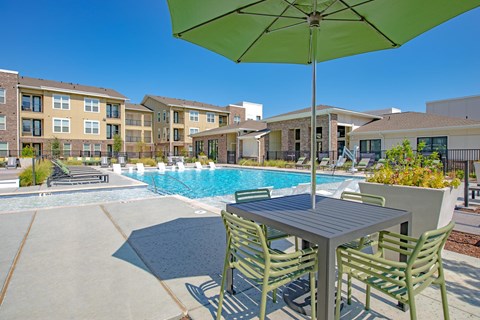 our apartments feature a pool and patio with a table and chairs