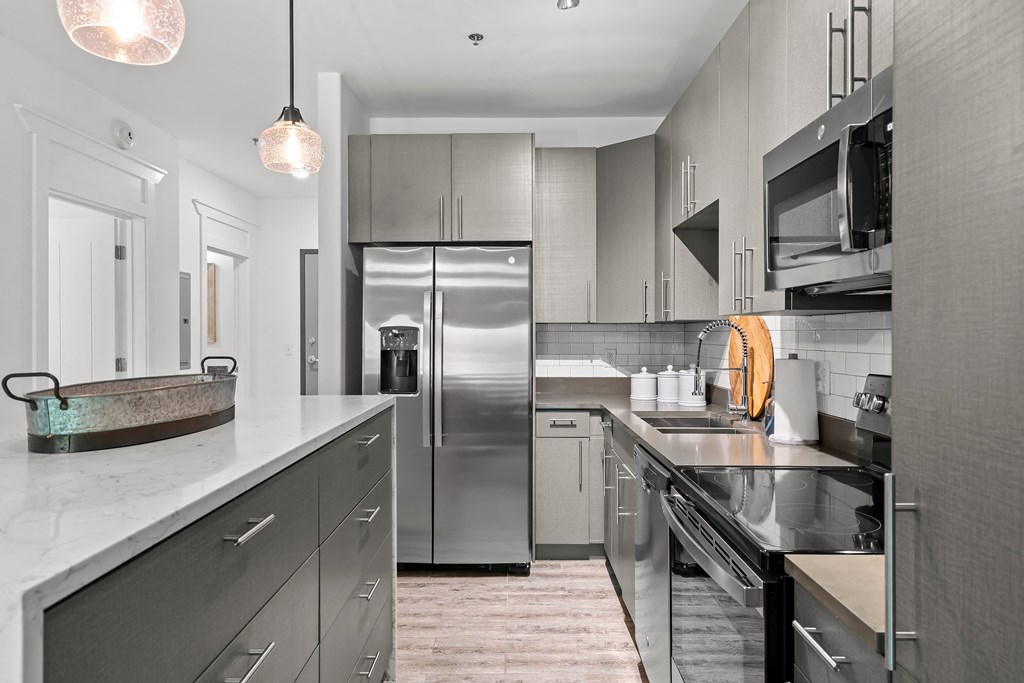 Kitchen with grey cabinets, waterfall island with stools, French door fridge
