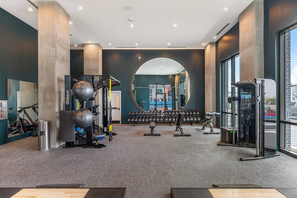 a gym with weights and cardio equipment in a room with windows