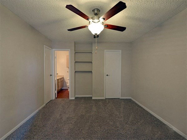 Model home bedroom with built in shelving, bathroom access, and door