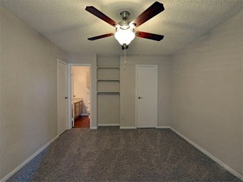 Model home bedroom with built in shelving, bathroom access, and door - Photo Gallery 3