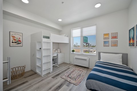 a bedroom with a bunk bed and a desk and a window