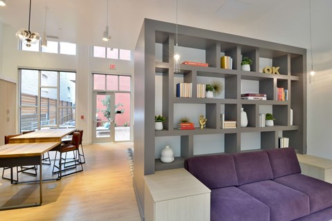 A modern living room with a purple couch and a grey bookshelf.