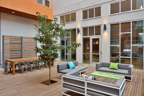 A patio with a tree, couch, and chairs.