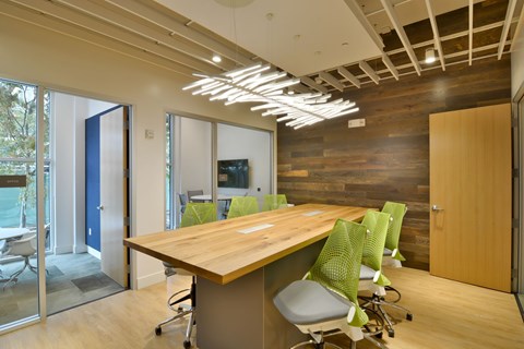 A conference room with a long table and green chairs.