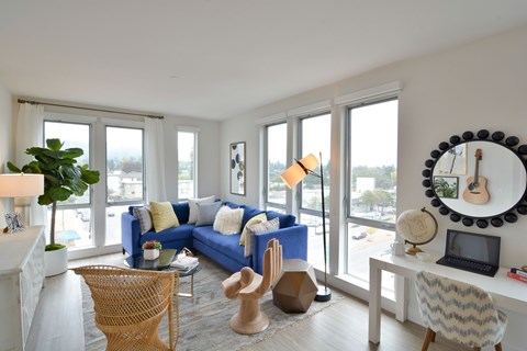 A living room with a blue couch and a guitar on the wall.