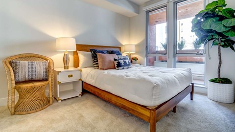 A bedroom with a bed, chair, and potted plant.