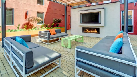 A patio with grey couches and a fireplace.