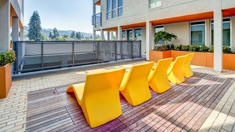 A row of yellow chairs are lined up on a brick patio.