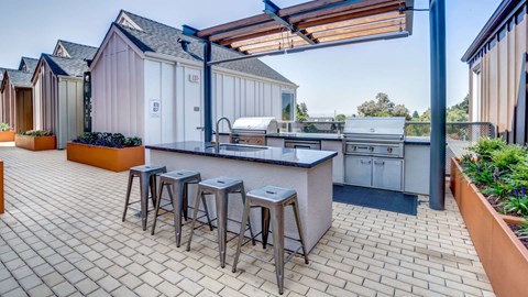 A patio with a bar and stools is surrounded by buildings.