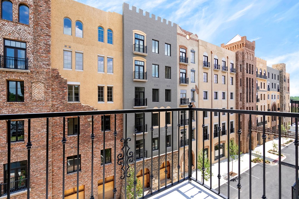 a balcony with a black railing and a view of a brick building