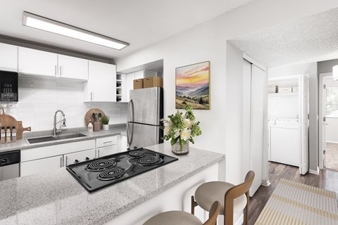 A modern kitchen with a black stove top and white cabinets.