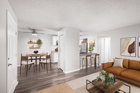 A living room with a brown couch and a dining table with chairs.