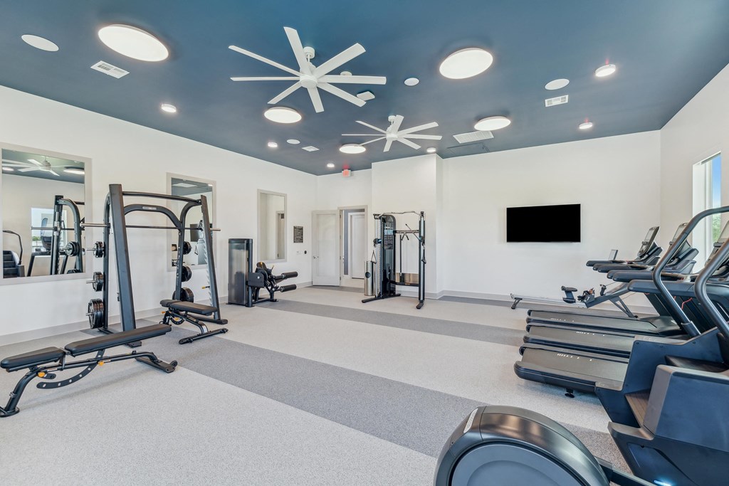 a gym with exercise equipment and a tv on the wall