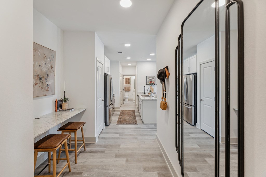 a long hallway with a kitchen and a counter with stools