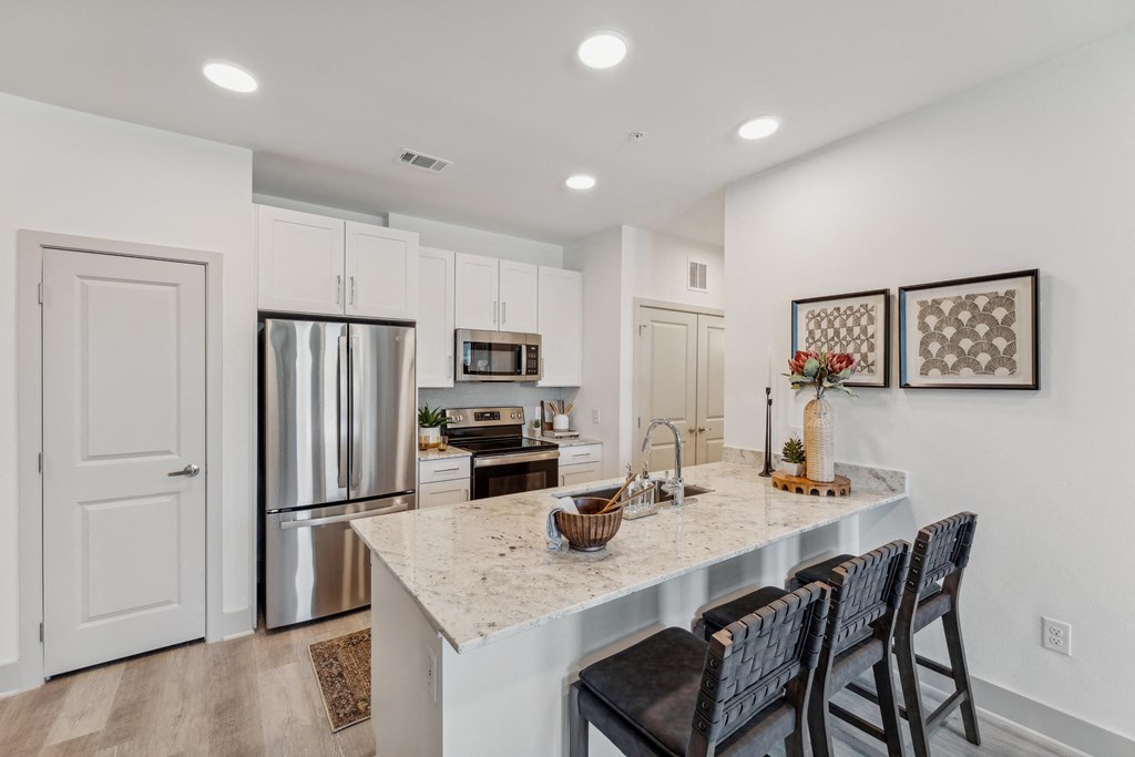 a kitchen with a marble counter top and a stainless steel refrigerator