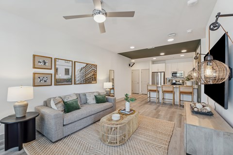 A living room with a grey couch and a ceiling fan.
