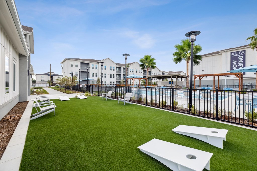 a yard with lounge chairs and grass next to a pool